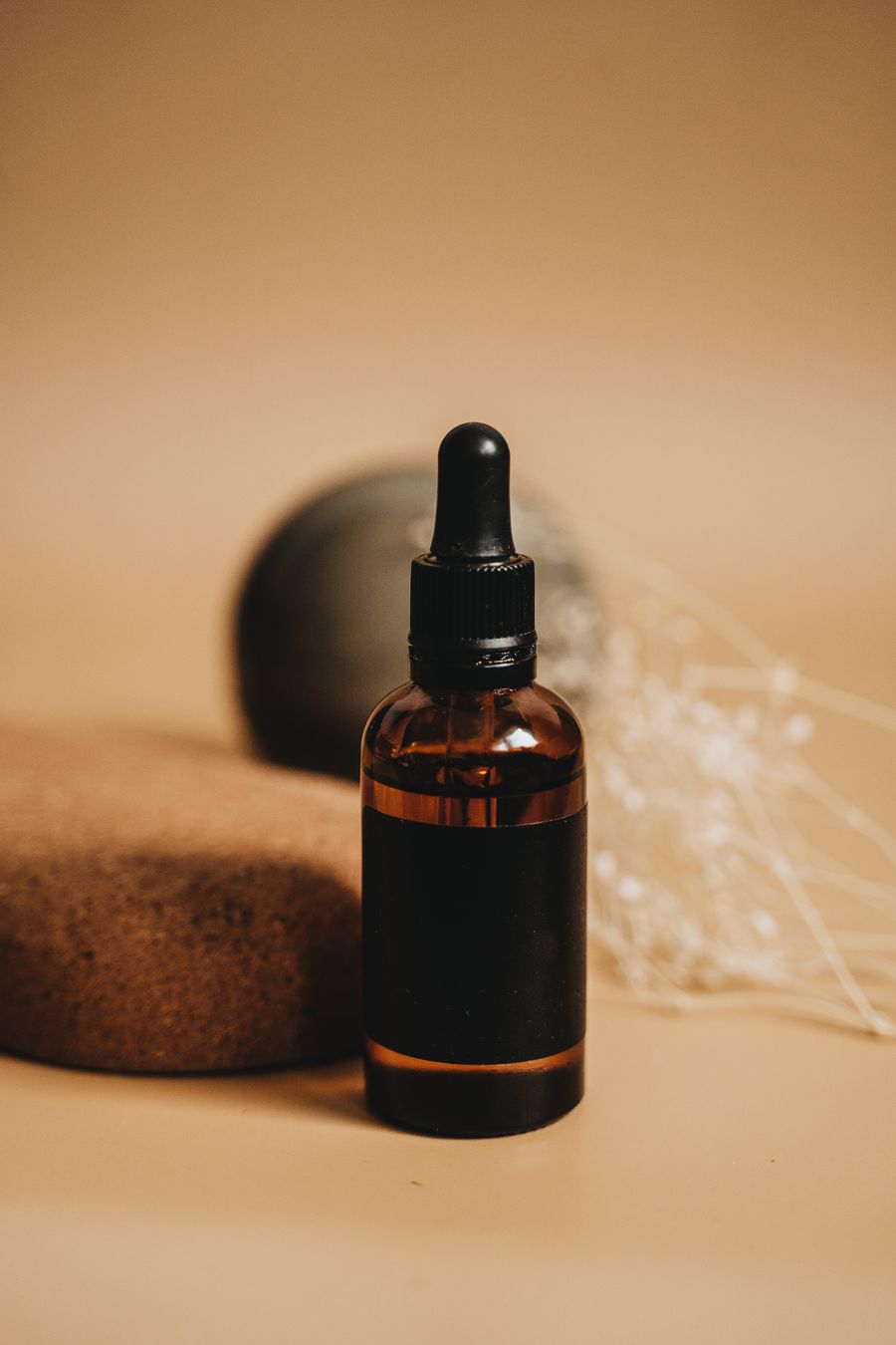 A plain amber glass bottle on a warm beige background